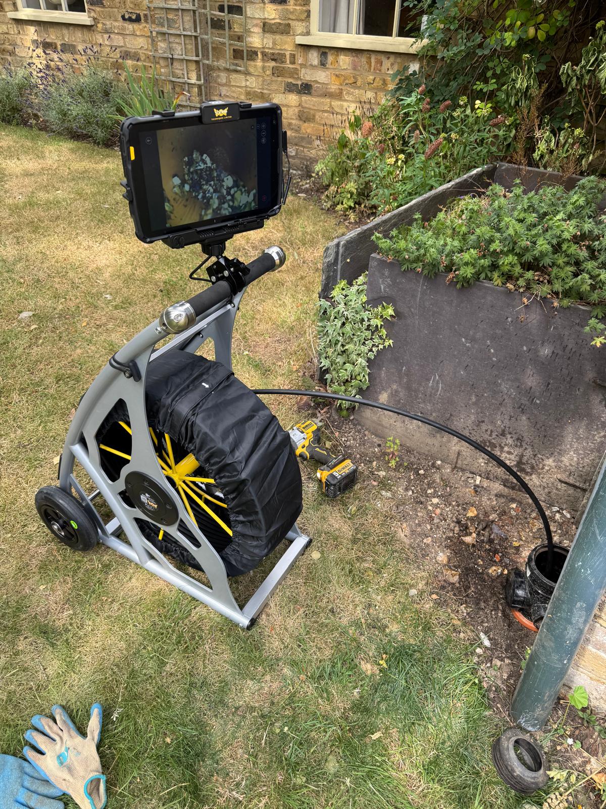 CCTV drain camera reel on lawn during survey