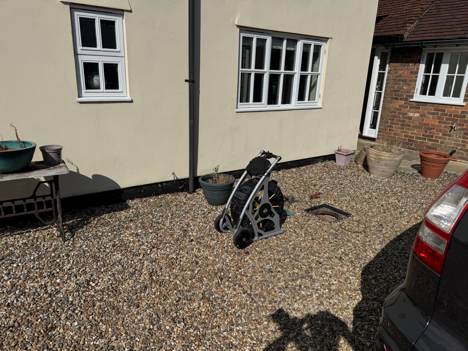 CCTV drainage survey equipment set up beside an open inspection chamber at a house